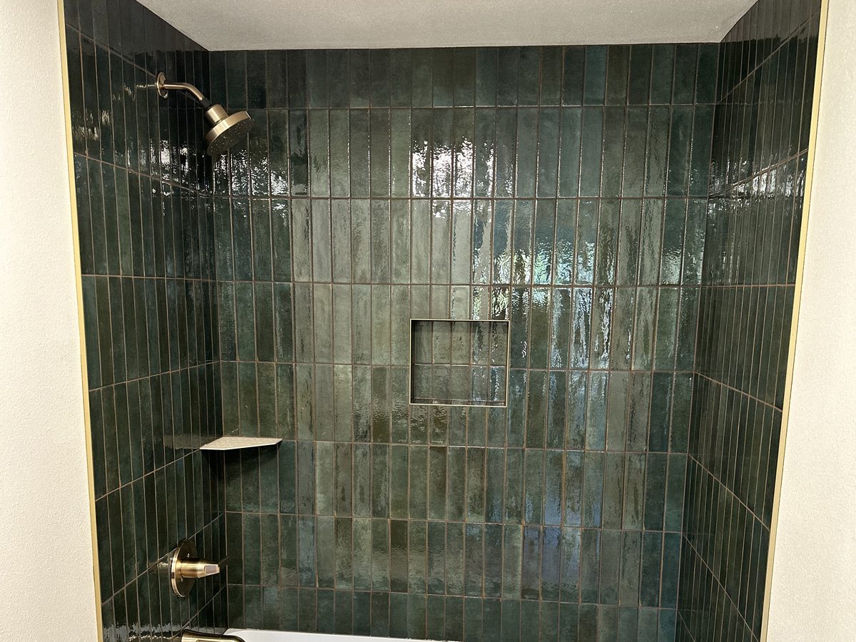 Bathroom remodel with a green tiled tub surround