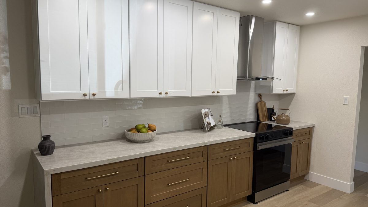Kitchen remodel by RNDLine Construction — white uppers, wood lowers, quartz counters