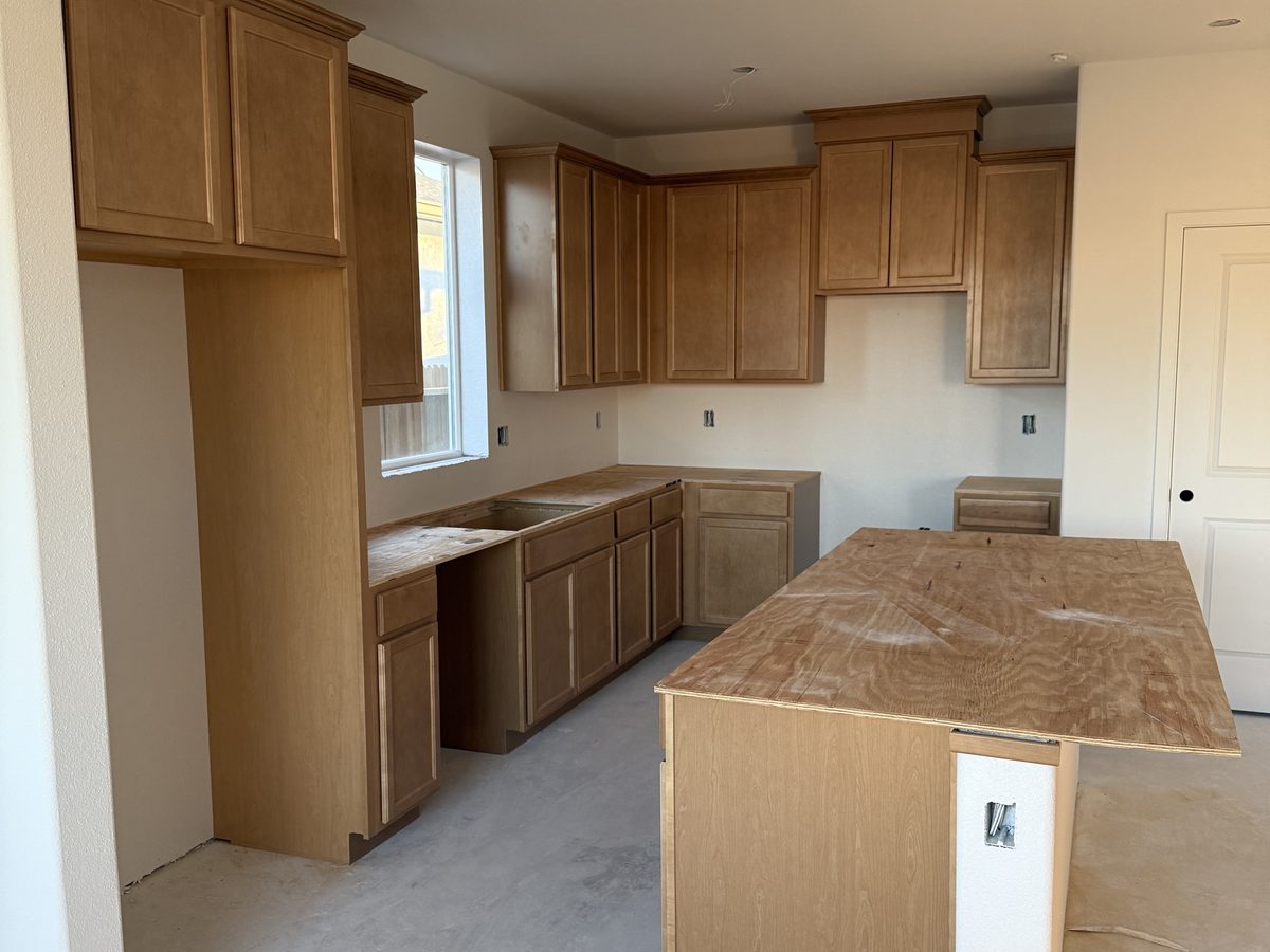 Kitchen with cabinets installed and plywood templates awaiting stone counters